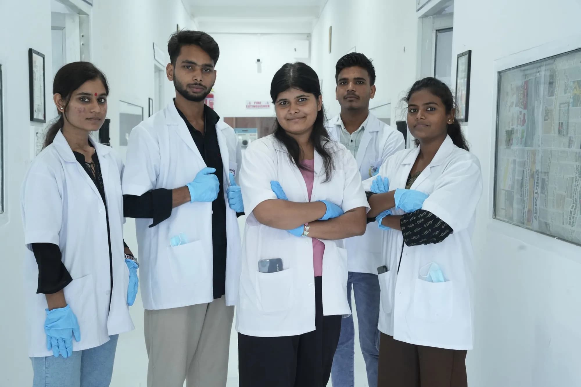Team of biotechnology trainees in lab coats standing together in the facility corridor